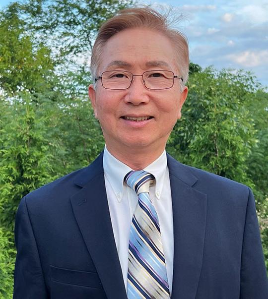 headshot of man with coat and tie, glasses